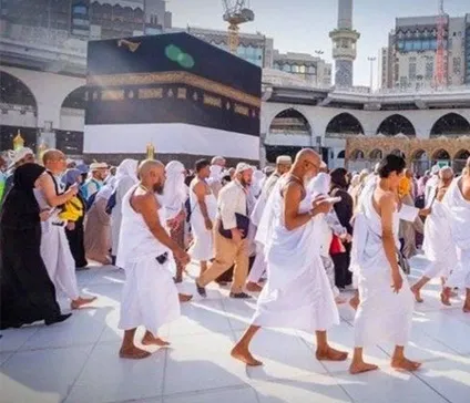 group of pilgrims dressed in white robes performing the Tawaf ritual